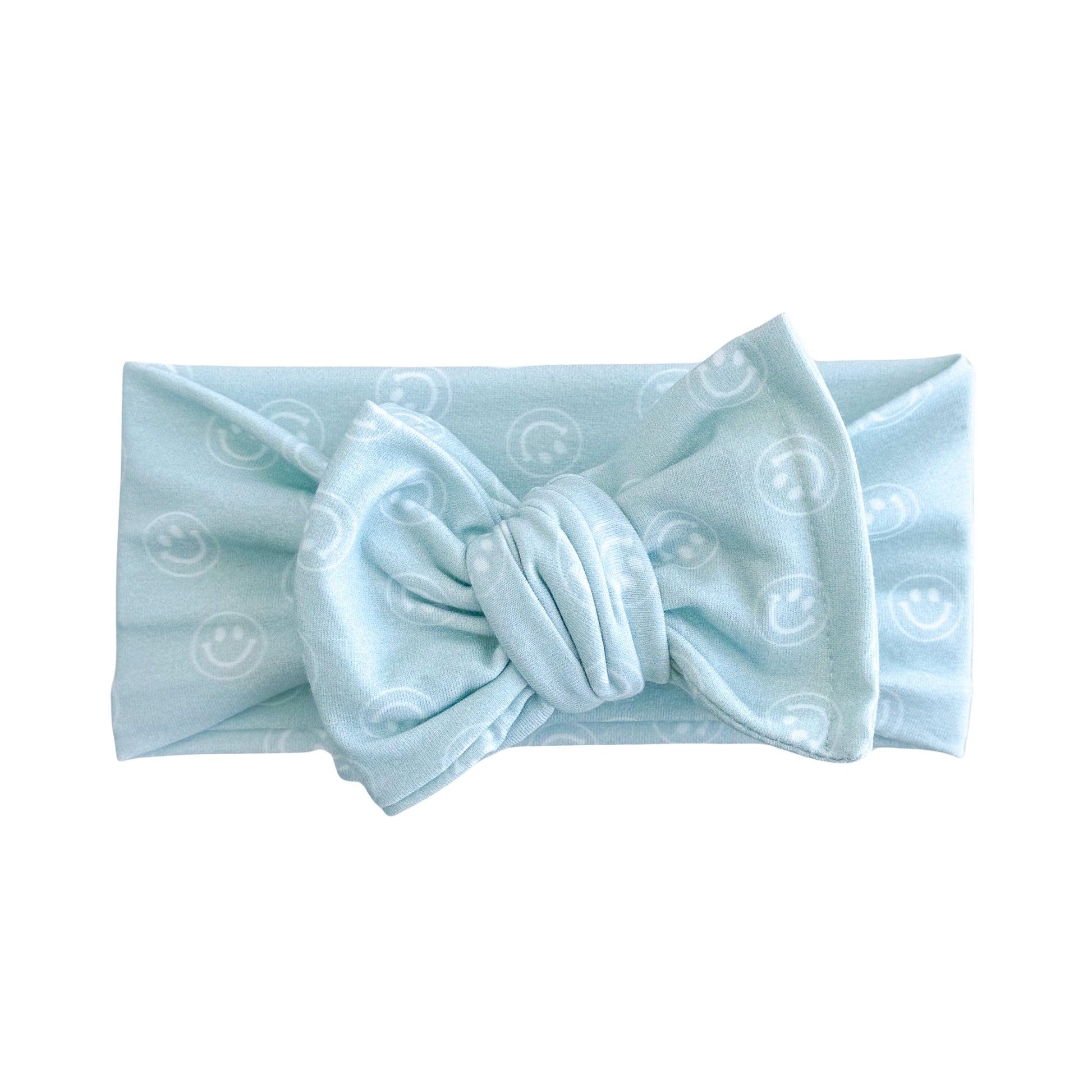 Oversized bow baby headband in light blue with simple white smiley face print, crafted from cotton jersey knit fabric, displayed on a white background