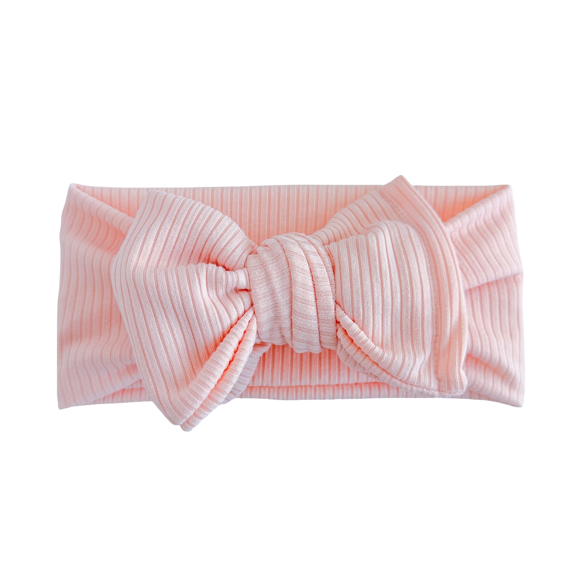 Oversized bow baby headband in light pink, crafted from ribbed knit fabric, displayed on a white background