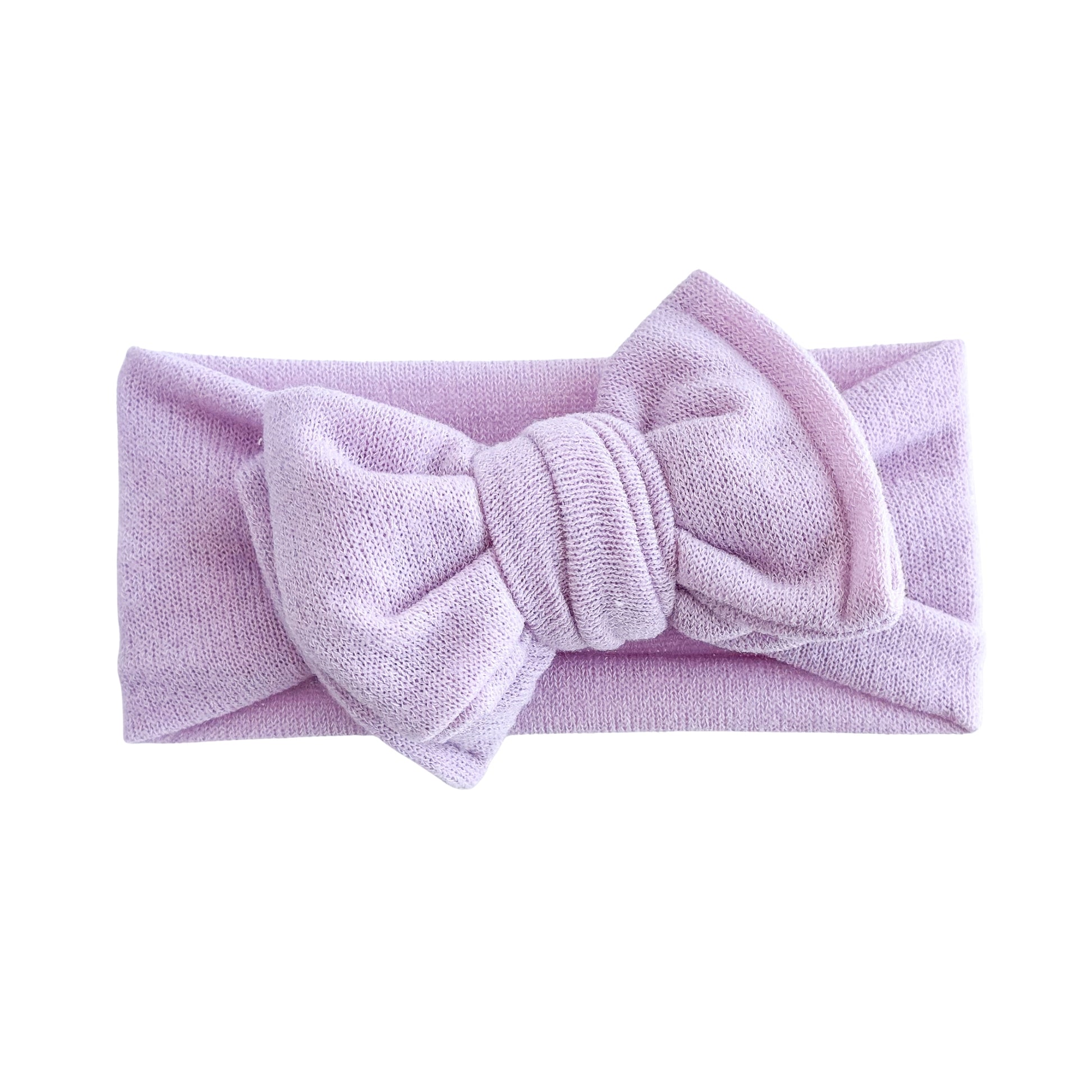 Oversized bow baby headband in lavender (light purple), crafted from stretchy terry cloth knit fabric, displayed on a white background