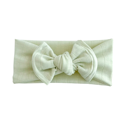 Oversized bow baby headband in lime green, crafted from wide ribbed knit fabric, displayed on a white background