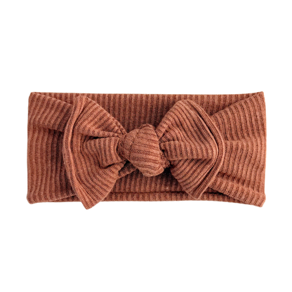 Brown ribbed headband with a large bow on a white background