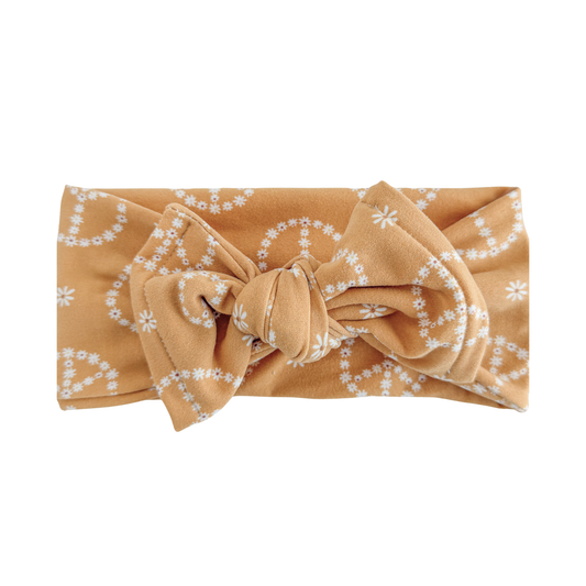 Marigold yellow headband with a bow and white floral pattern on a white background