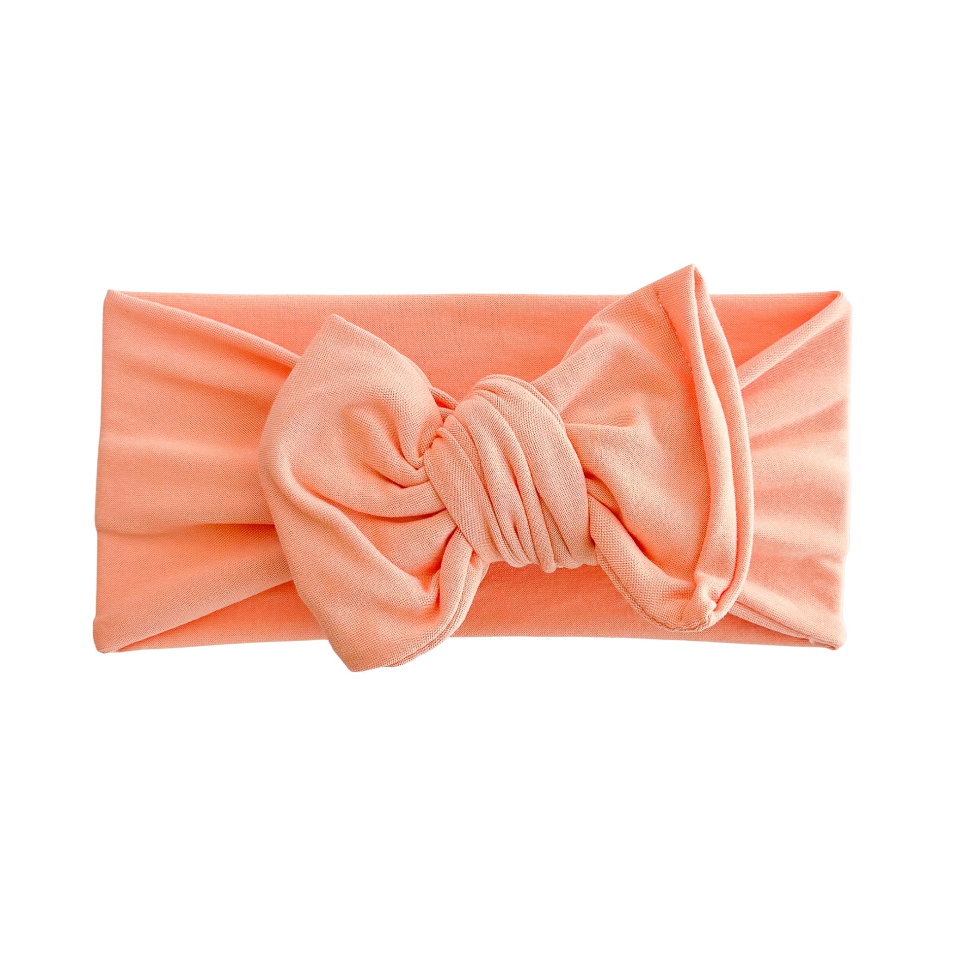 Oversized bow baby headband in melon (bright light orange), crafted from double brushed knit fabric, displayed on a white background