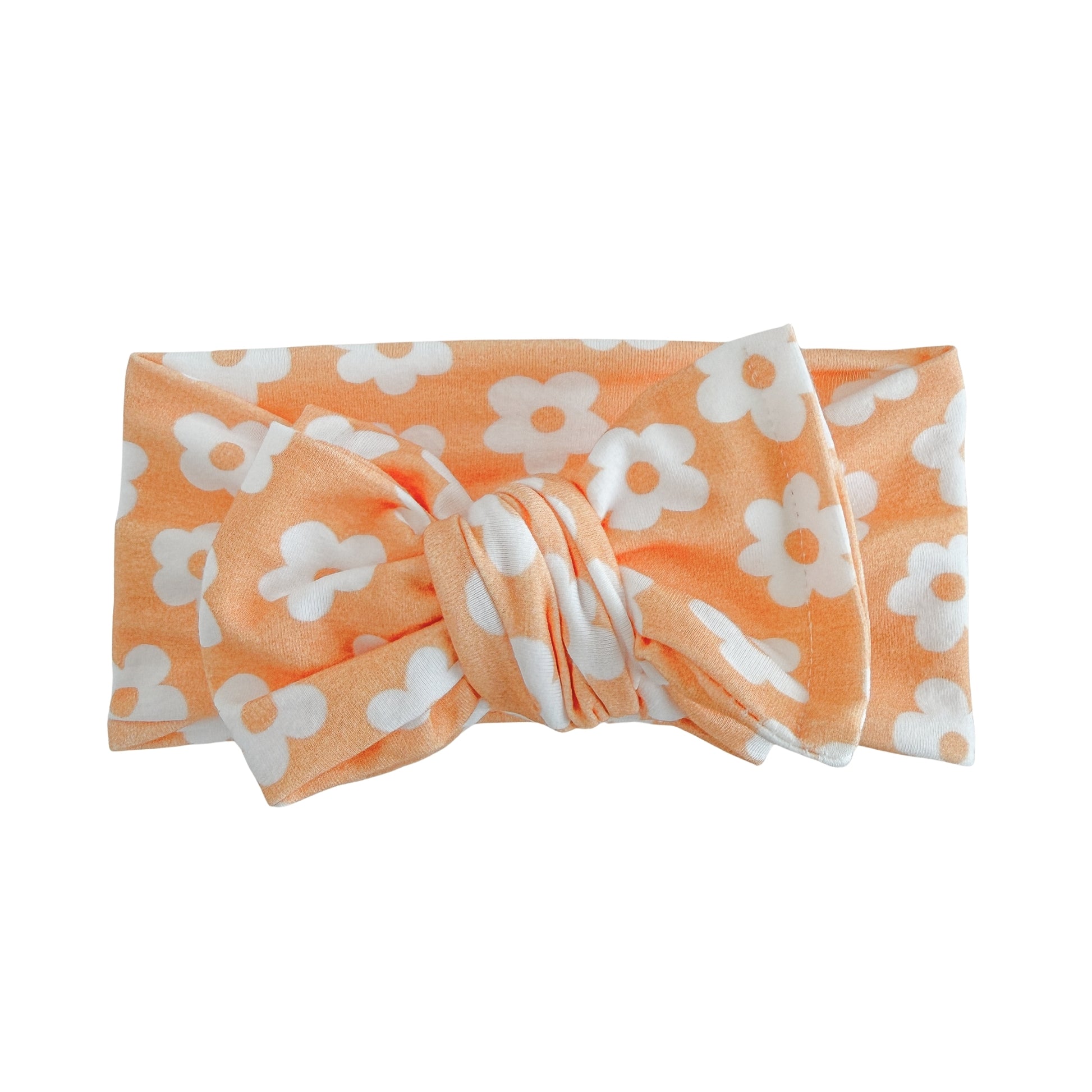 Oversized bow baby headband in orange with white retro daisy print, crafted from cotton jersey knit fabric, displayed on a white background