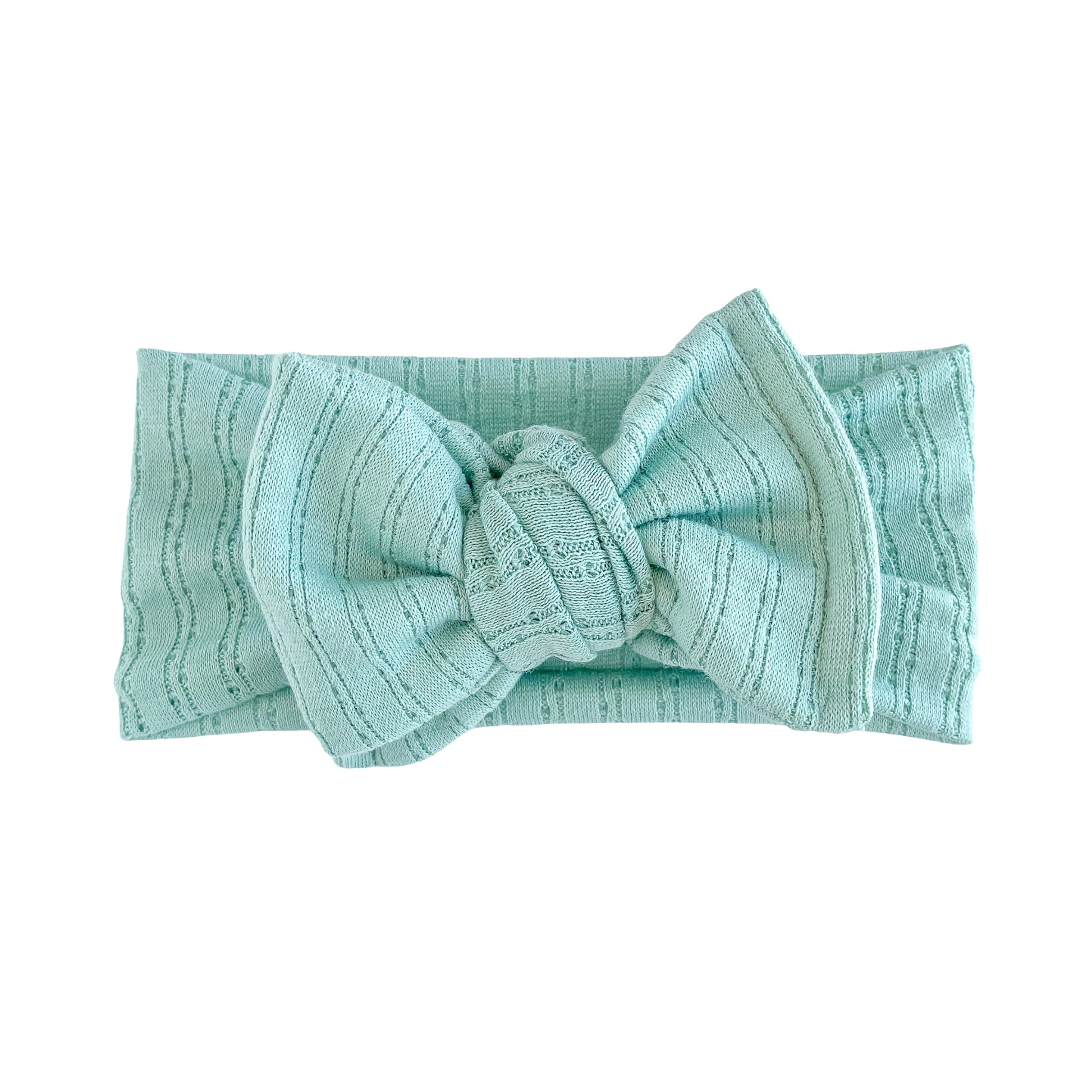 Top knot baby headband in mint green, crafted from pointelle knit fabric, displayed on a white background