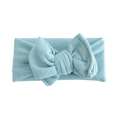 Oversized bow baby headband in mint green blue, crafted from stretchy terry cloth knit fabric, displayed on a white background