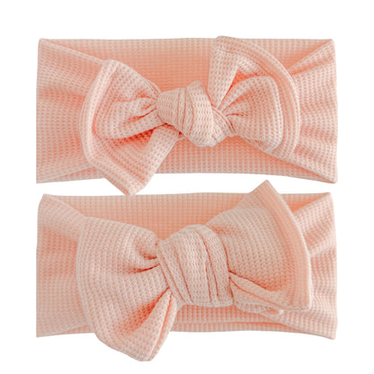 Baby girl headbands in top knot and oversized bow styles in peachy pink, made from waffle knit fabric