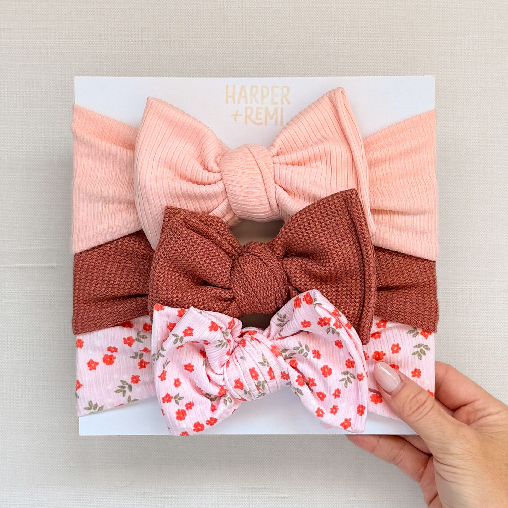 Set of oversized baby bows hand held on a branded card.