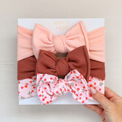Set of oversized baby bows hand held on a branded card.