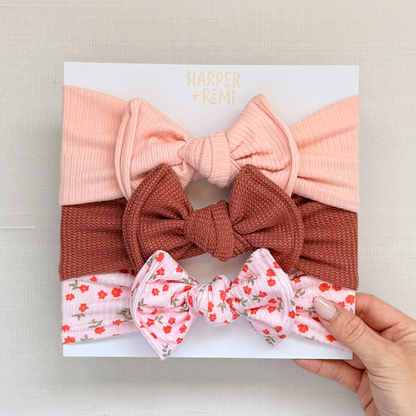 Set of hair bows in green, pink, and beige on a branded card.