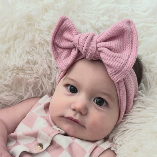 Baby wearing a large dusty pink waffle top knot