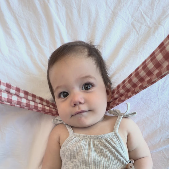 Tutorial showing how to tie a ribbed top knot bow on a baby's head.