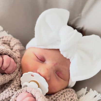 Newborn baby girl announcement video showing crochet knit sweater and white pointelle top knot bow headband.