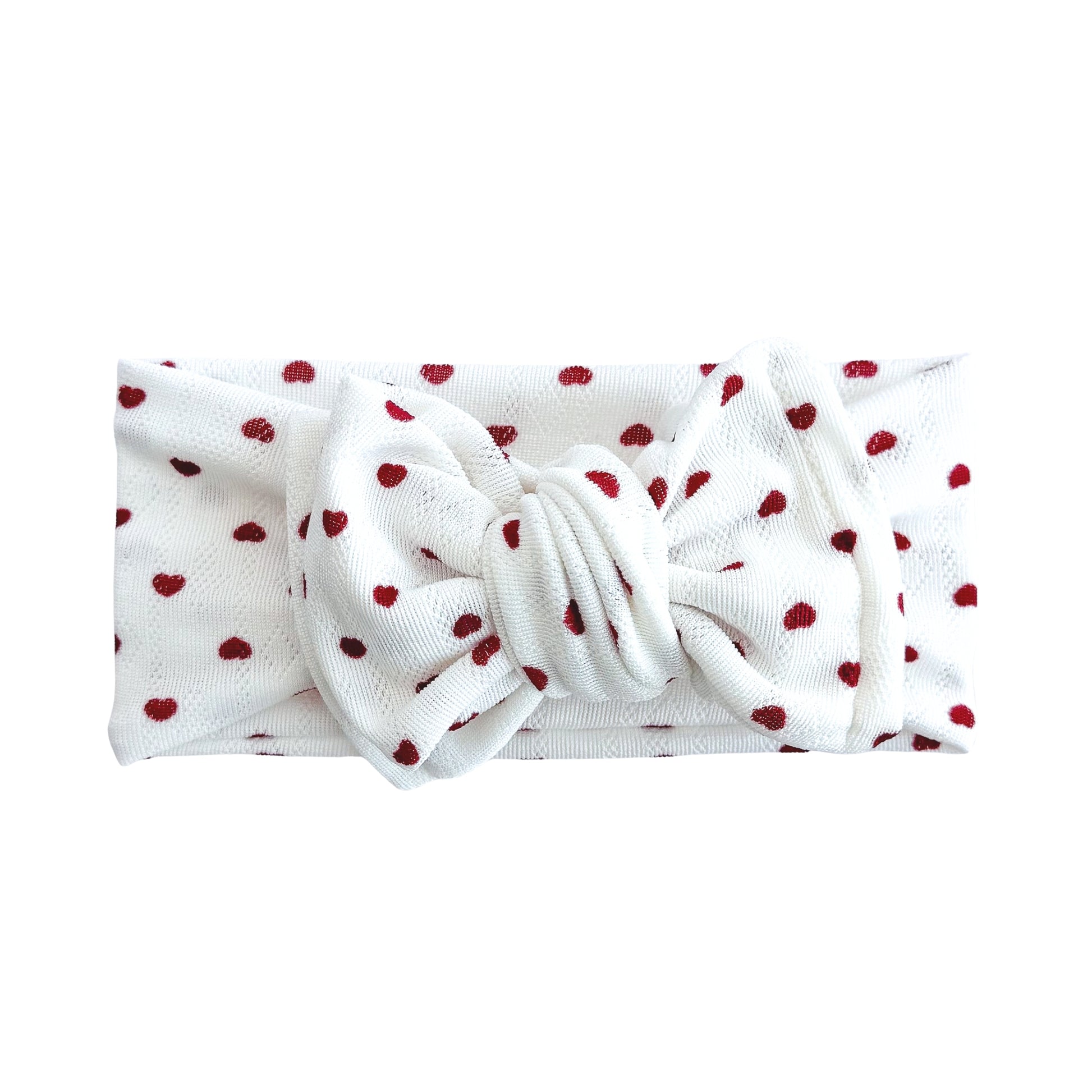 Oversized bow baby headband in white with dark red tiny heart print, crafted from jacquard knit fabric, displayed on a white background