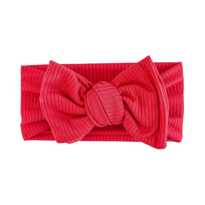 Oversized bow baby headband in red, crafted from ribbed knit fabric, displayed on a white background