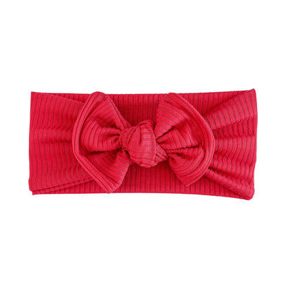 Red ribbed top knot headband with a large bow on a white background