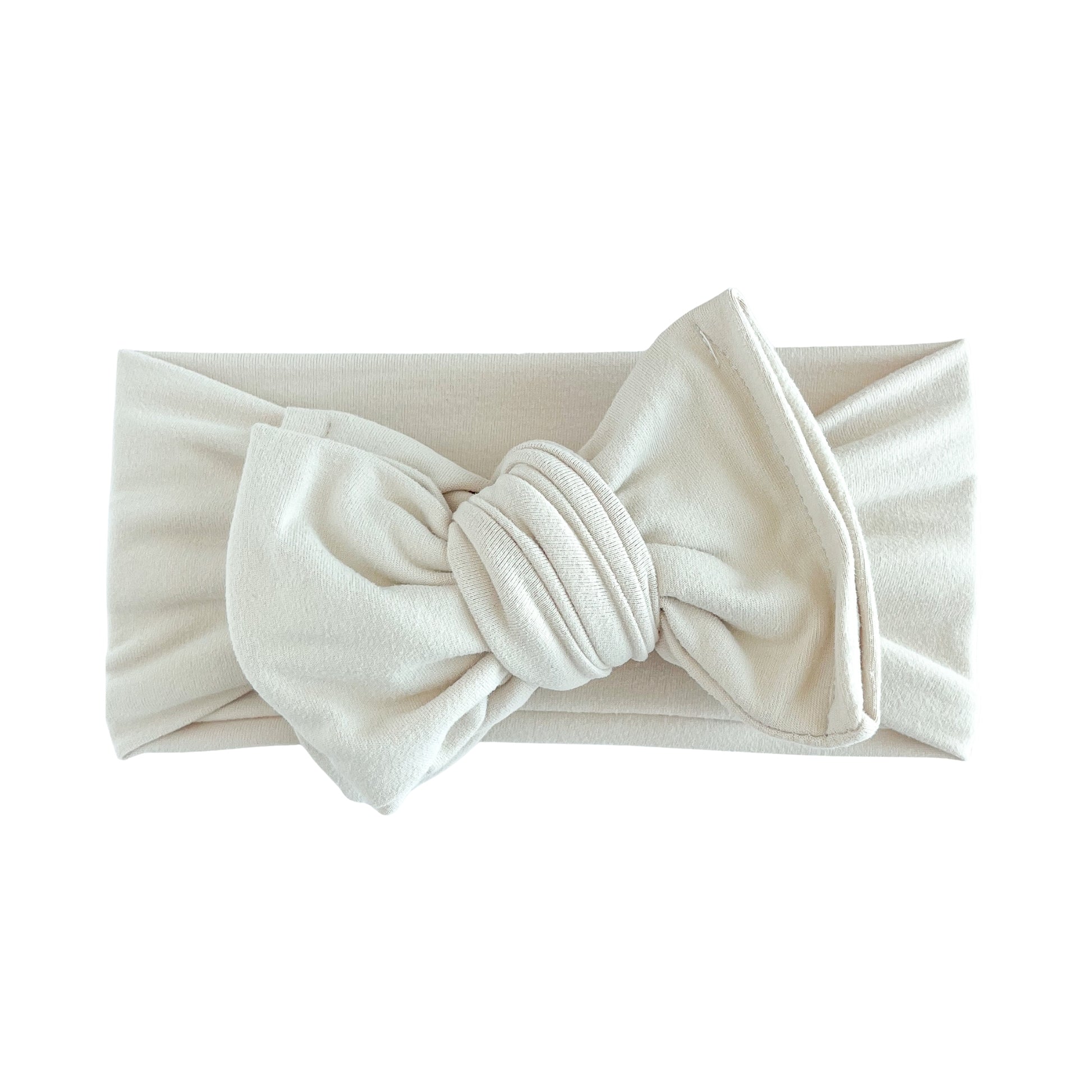 Oversized bow baby headband in sand (beige), crafted from double brushed knit fabric, displayed on a white background