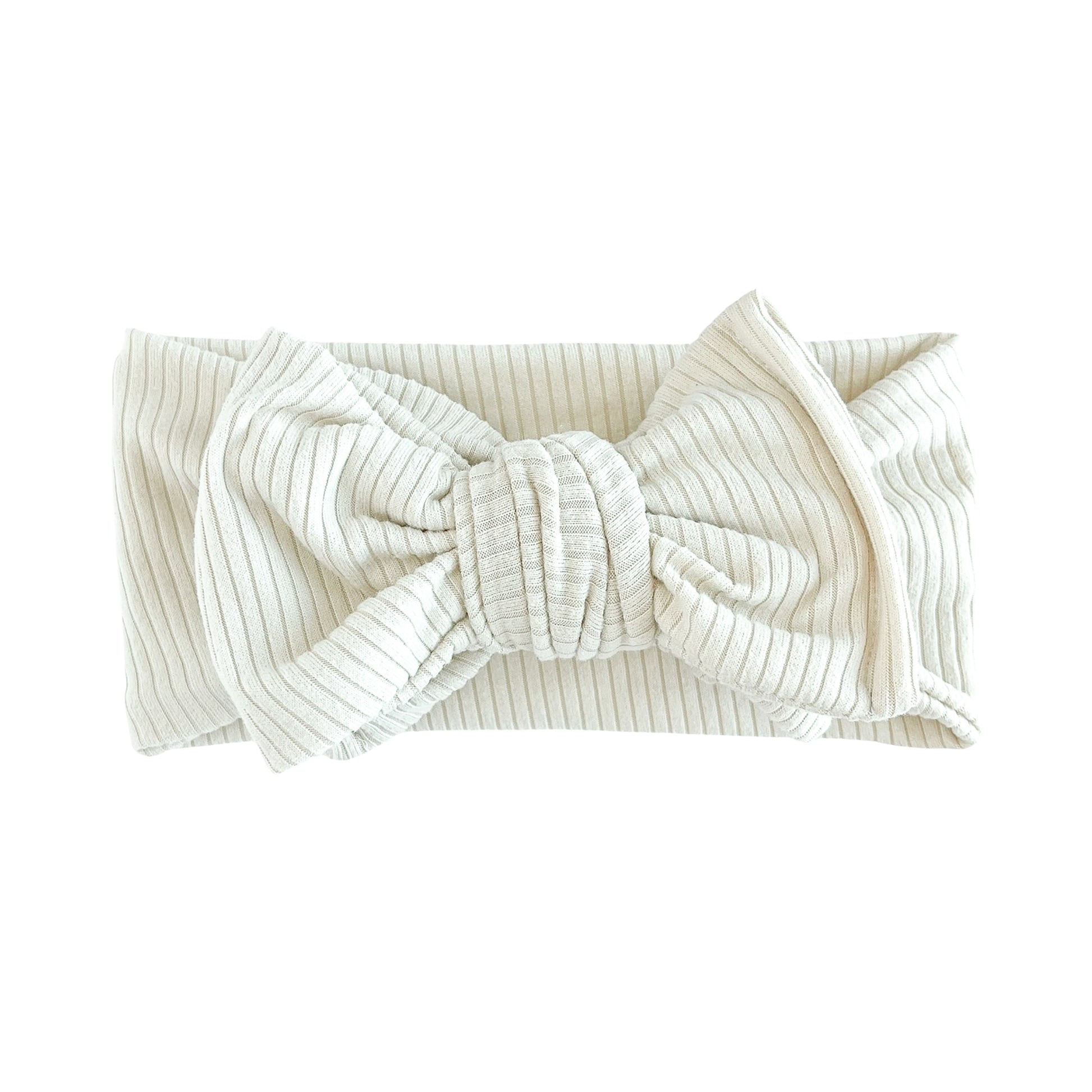 Oversized bow baby headband in sand (beige), crafted from ribbed knit fabric, displayed on a white background
