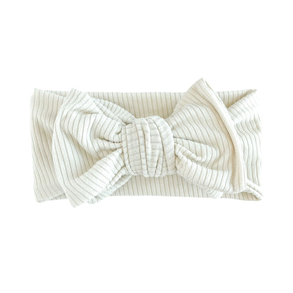 Oversized bow baby headband in sand (beige), crafted from ribbed knit fabric, displayed on a white background