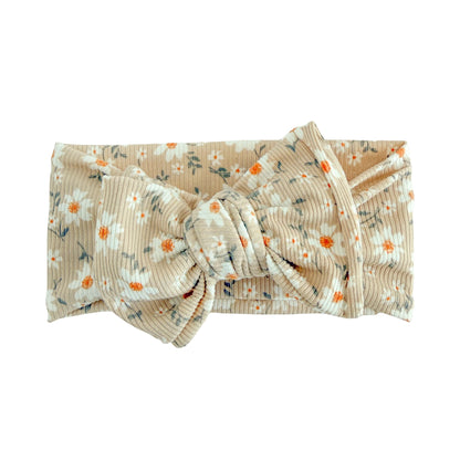 Oversized bow baby headband in taupe daisy floral print, crafted from ribbed knit fabric, displayed on a white background