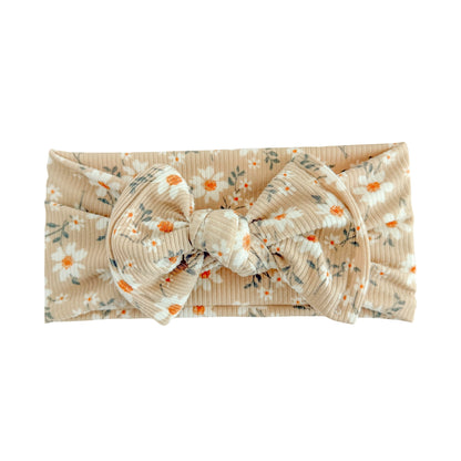 Top knot baby headband in taupe daisy floral print, crafted from ribbed knit fabric, displayed on a white background