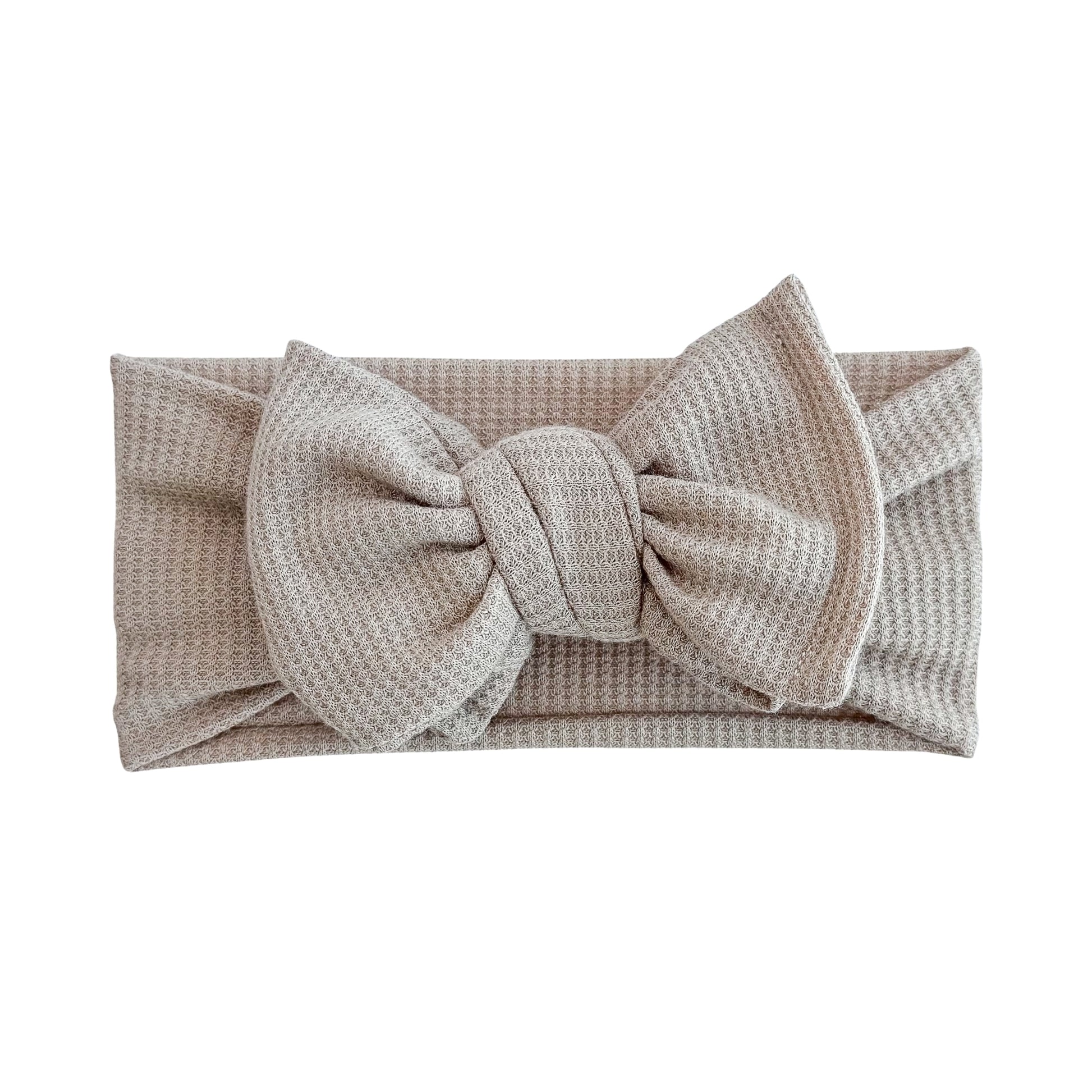Oversized bow baby headband in taupe, crafted from waffle knit fabric, displayed on a white background