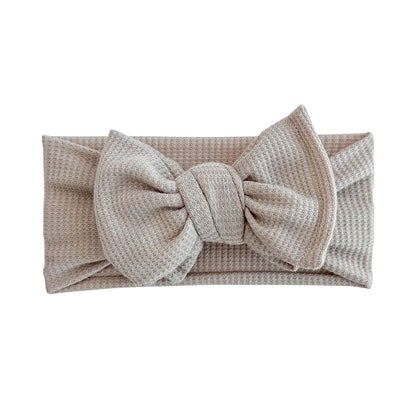 Oversized bow baby headband in taupe, crafted from waffle knit fabric, displayed on a white background