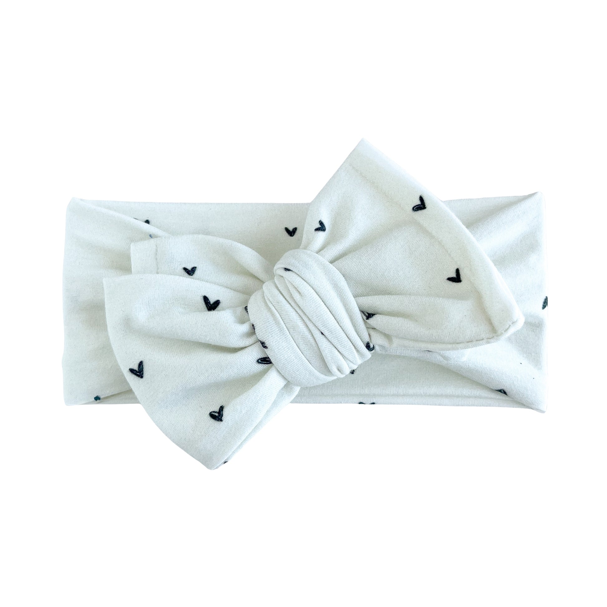 Oversized bow baby headband in off white with dainty black heart print, crafted from cotton jersey knit fabric, displayed on a white background