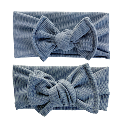 Two blue textured headbands with large bows on a white background. Top is a top knot, bottom is an oversized bow.
