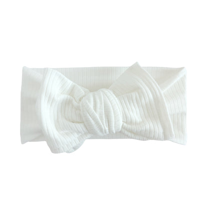 Oversized bow baby headband in white, crafted from ribbed cotton jersey knit fabric, displayed on a white background