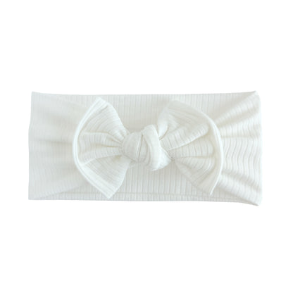 Top knot baby headband in white, crafted from ribbed cotton jersey knit fabric, displayed on a white background