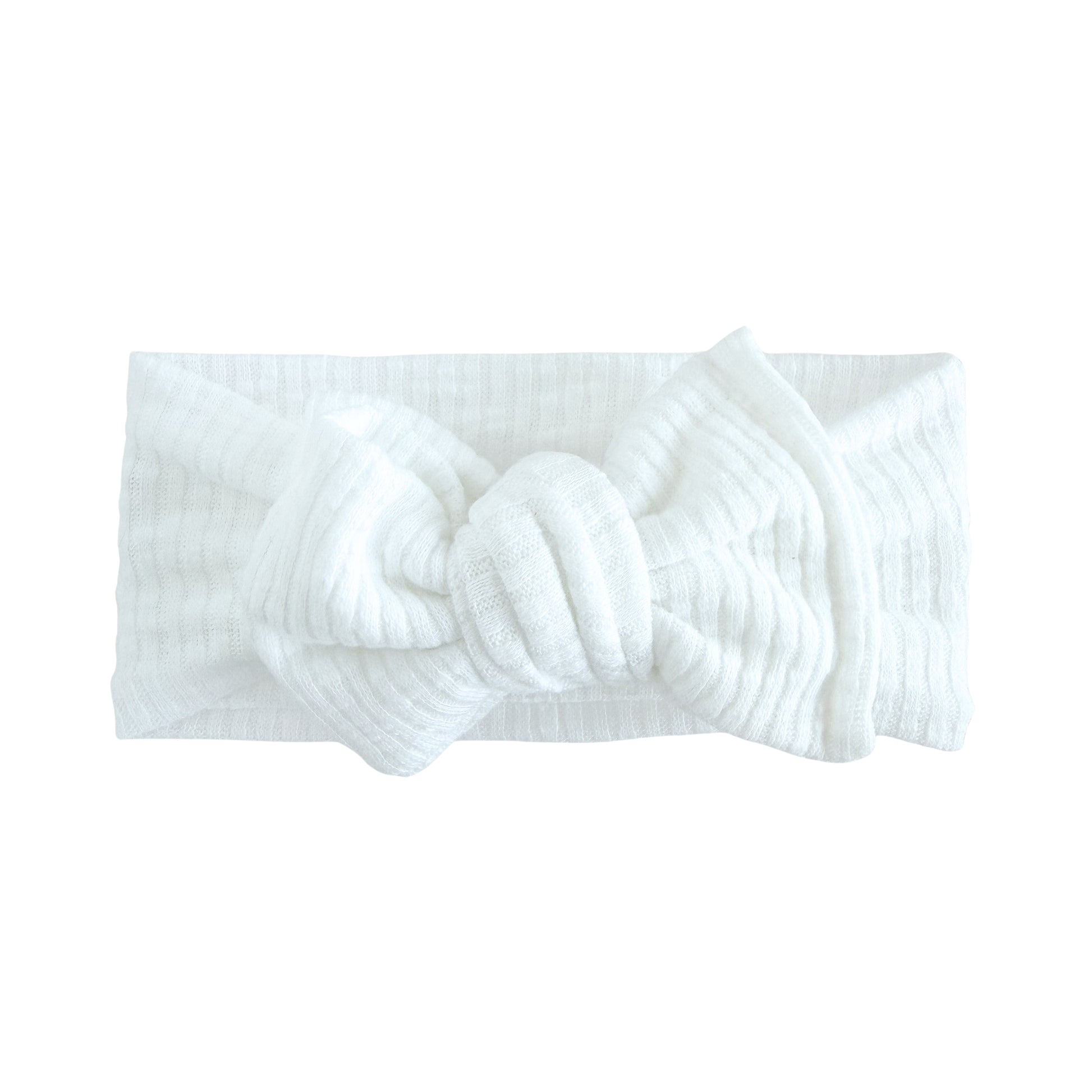 Oversized bow baby headband in white, crafted from ribbed knit fabric, displayed on a white background