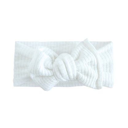 Oversized bow baby headband in white, crafted from ribbed knit fabric, displayed on a white background