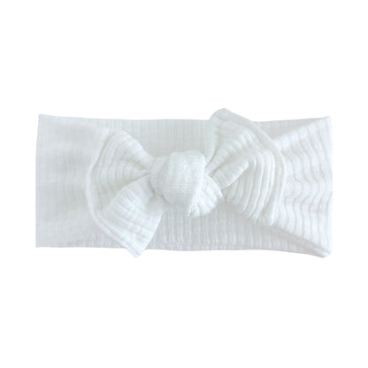 Flat lay of a white ribbed top knot headband with white background.