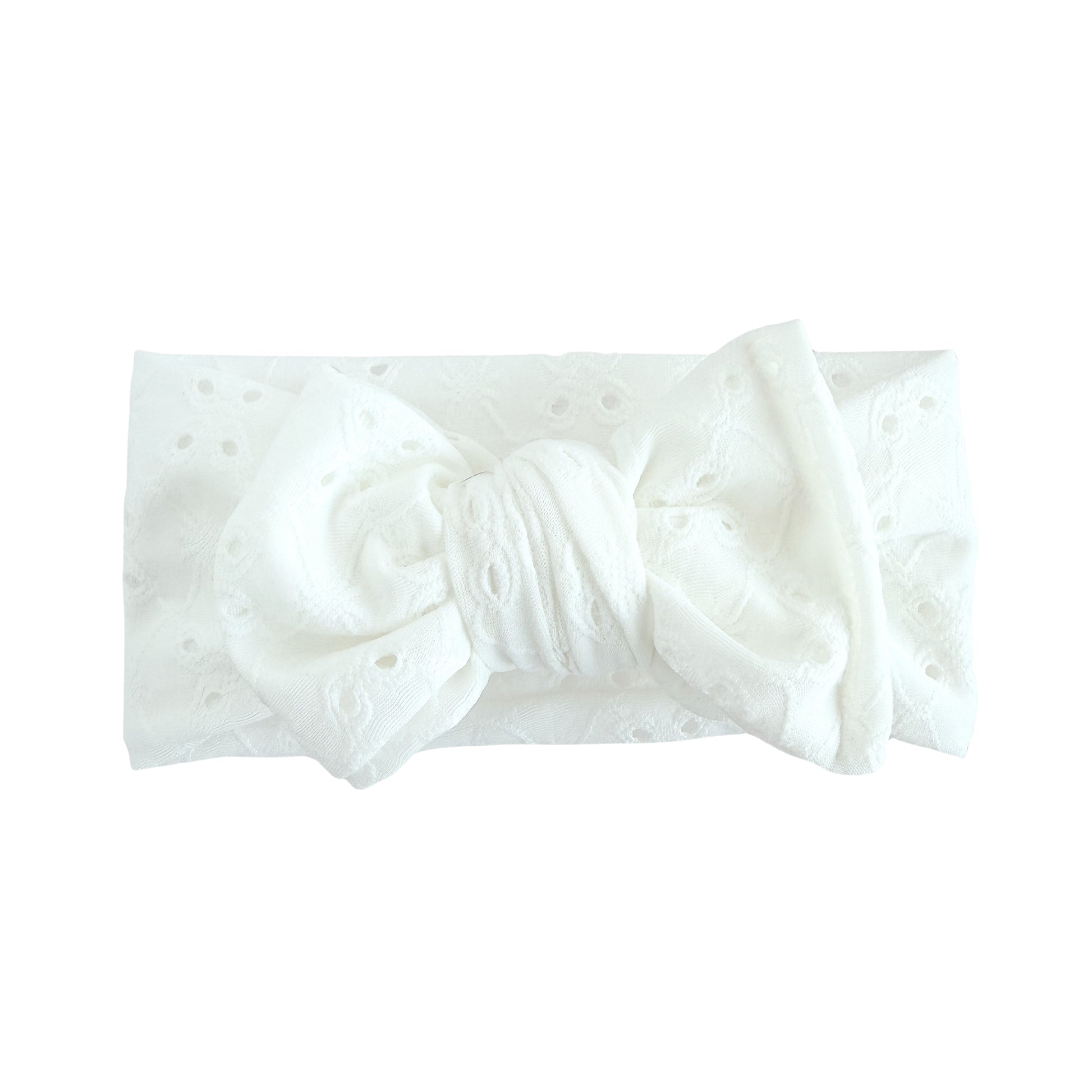 Oversized bow baby headband in white, crafted from stretchy eyelet knit fabric, displayed on a white background