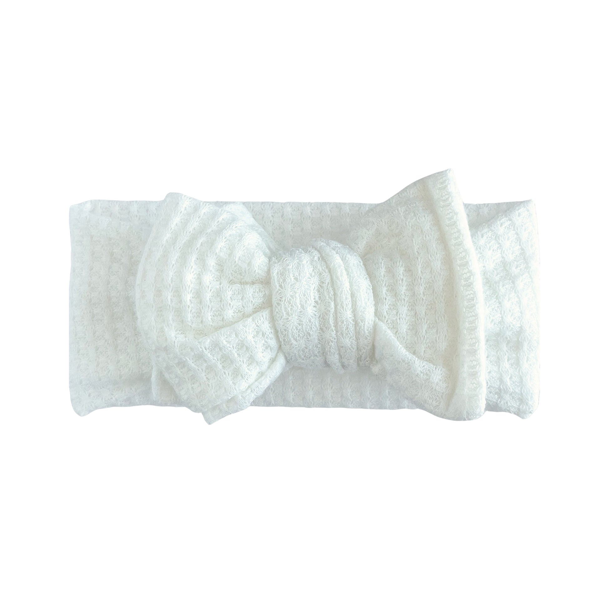 Oversized bow baby headband in white, crafted from honeycomb waffle knit fabric, displayed on a white background