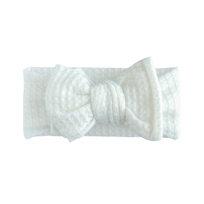 Oversized bow baby headband in white, crafted from honeycomb waffle knit fabric, displayed on a white background