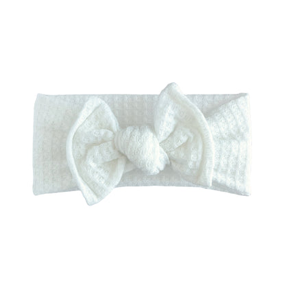 Top knot baby headband in white, crafted from honeycomb waffle knit fabric, displayed on a white background
