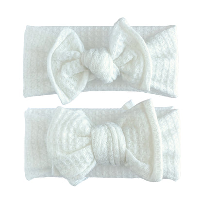 Baby girl headbands in top knot and oversized bow styles in white, made from honeycomb waffle knit fabric