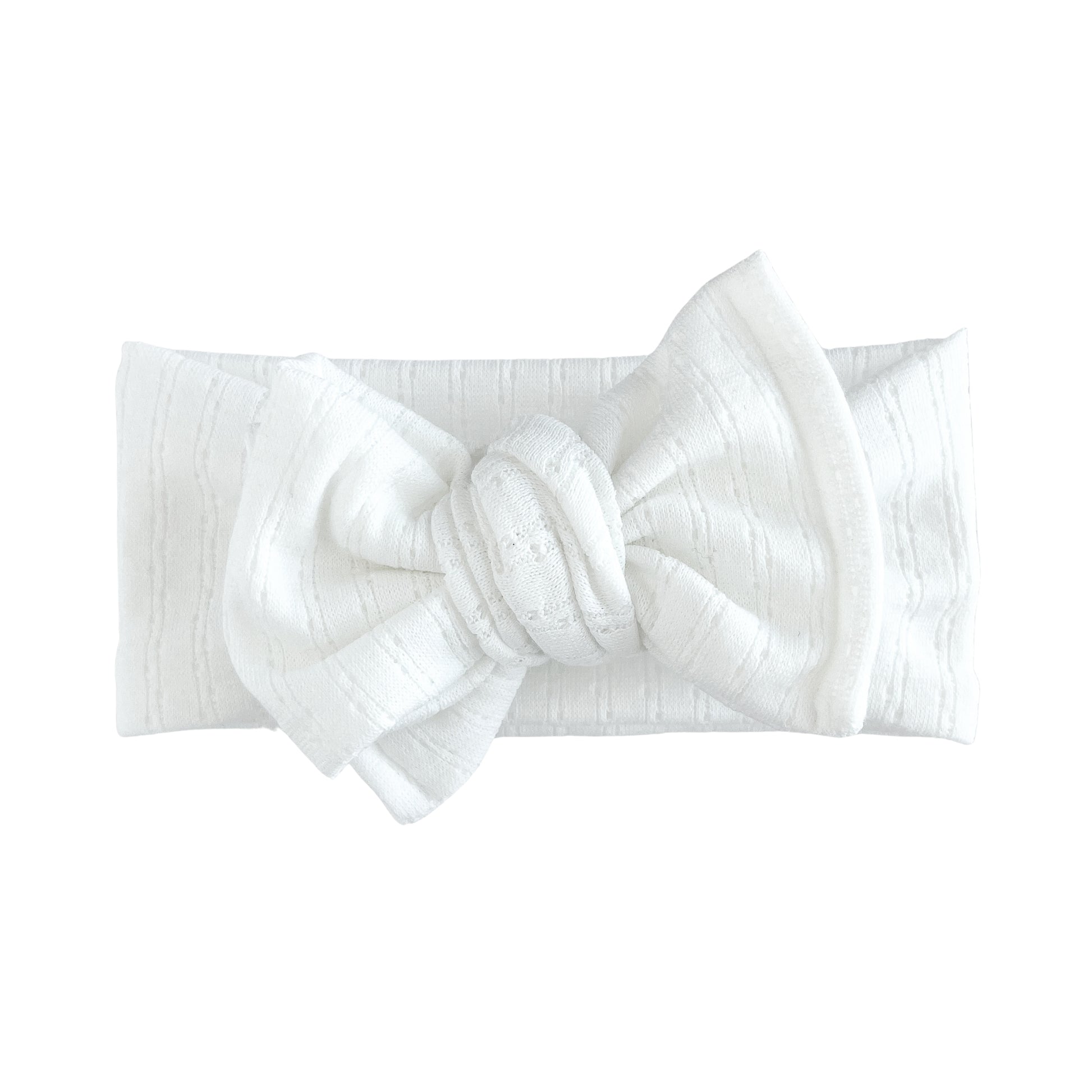Oversized bow baby headband in white, crafted from pointelle knit fabric, displayed on a white background