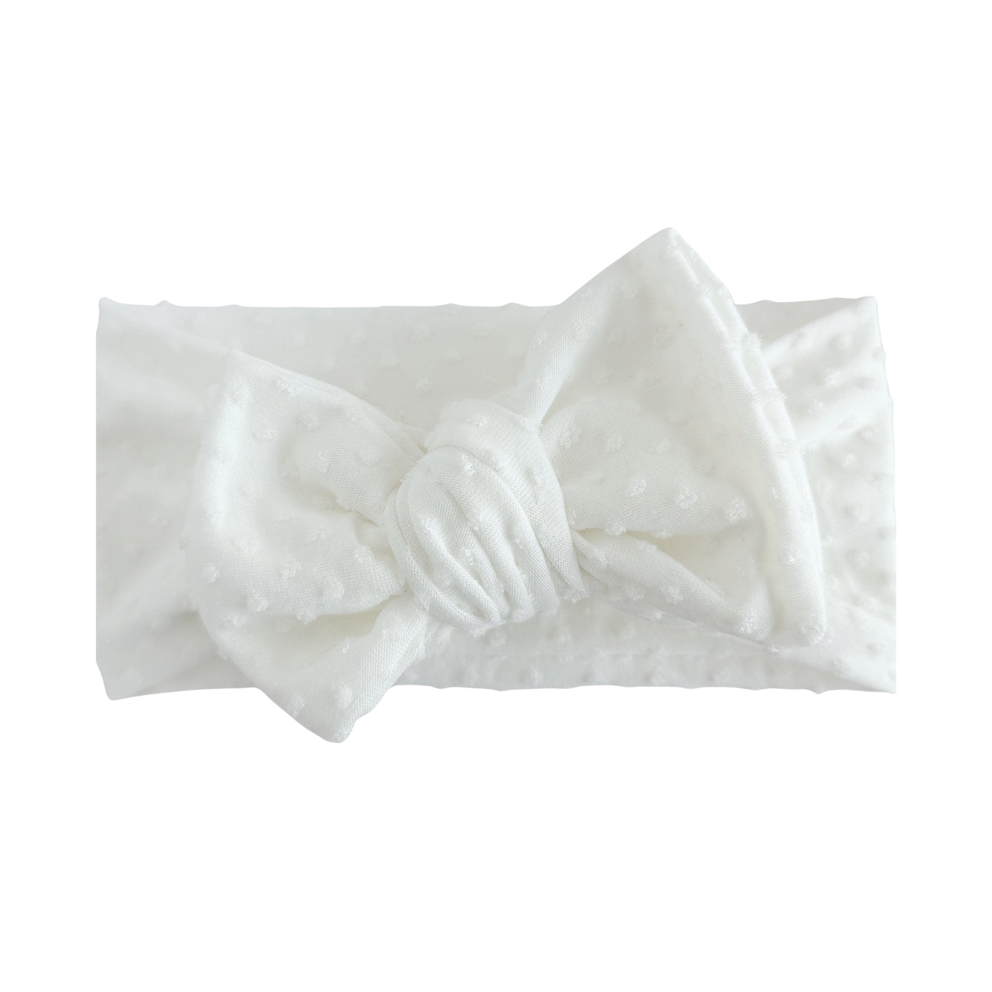 Oversized bow baby headband in white, crafted from Swiss dots knit fabric, displayed on a white background