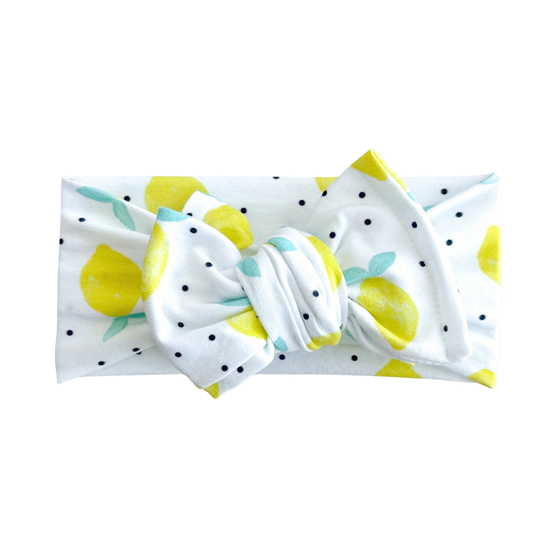 Oversized bow baby headband in white with yellow lemon and tiny black dots print, crafted from cotton jersey knit fabric, displayed on a white background